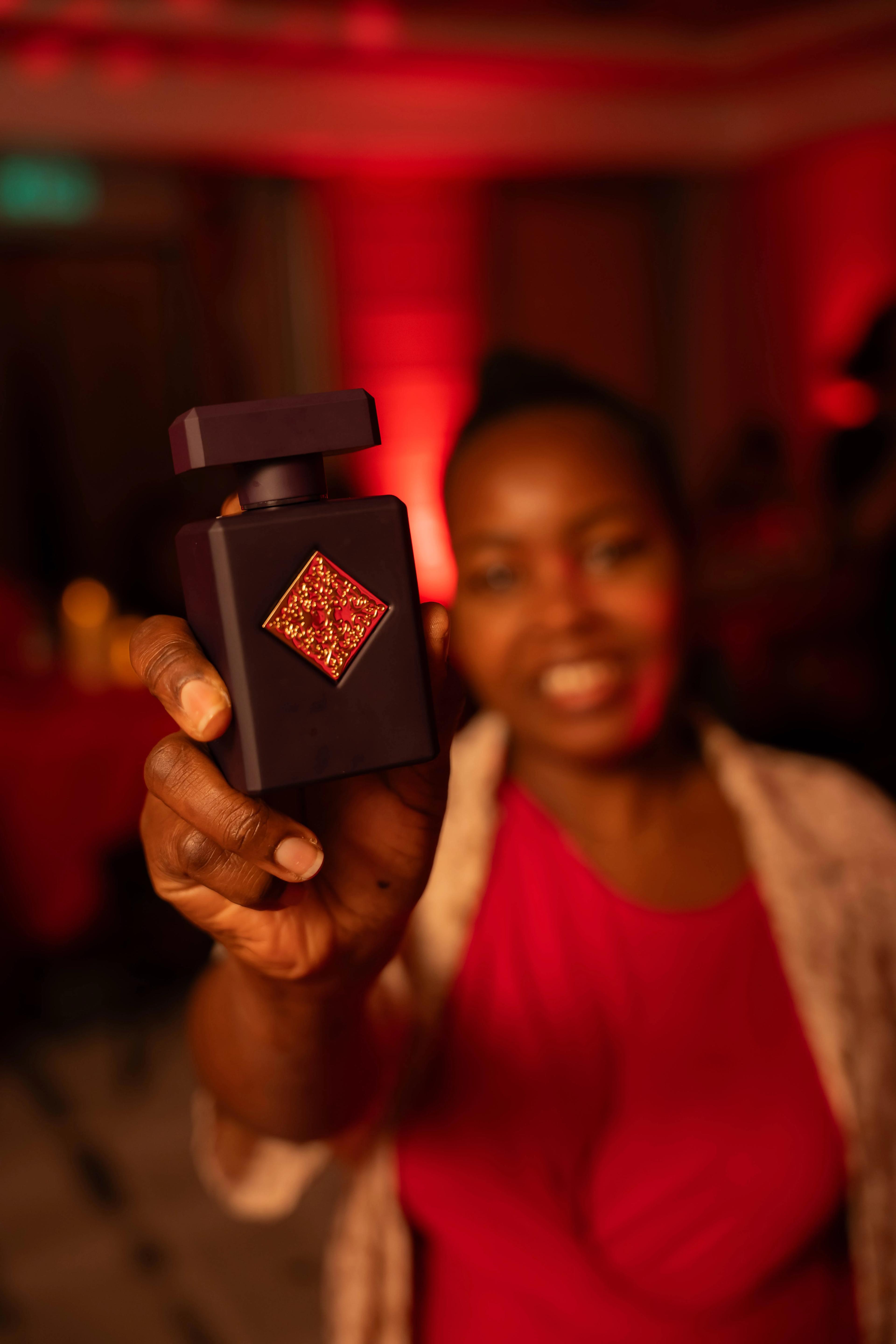 Behind-the-scenes image of a perfume ad shoot, model posing with product in elegant setting.